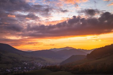Günbatımında gökyüzünde renkli bulutlar olan sonbahar kırsal manzarası.