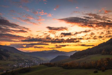 Günbatımında gökyüzünde renkli bulutlar olan sonbahar kırsal manzarası.