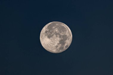 A serene view of the full moon against a deep, blue night sky. Detailed lunar surface visible. Captivating celestial scene.
