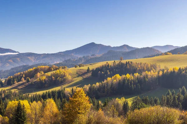 Scenic landscape view of an autumn mountain valley with lush forests rolling hills and clear blue sky. Northwest of Slovakia, Europe.