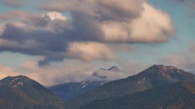 Bulutlu bir gökyüzünün altındaki dağlar. Ağaçlandırılmış yuvarlanan tepeler açık mavi gökyüzü arka planına karşı gri kümülüs bulutlarıyla kaplıdır. Slovakya, Avrupa 'daki Mala Fatra ulusal parkı. Zaman ayarlı görüntüler.