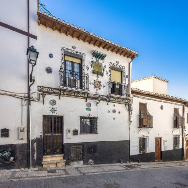 Granada, İspanya - 5 Eylül 2024: Güneşli bir günde renkli fayans aksanı ve balkonları olan süslü, beyaz bir bina.