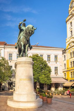Pecs, Macaristan - 13 Temmuz 2024: Szechenyi Meydanı. Güneşli bir günde binicilik heykeli: şehir meydanında tarihi bir anıt. Mimari güzellik, kültürel mirasla buluşur..