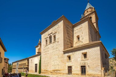 Granada, İspanya - 5 Eylül 2024: Santa Maria de la Alhambra Kilisesi. Açık mavi gökyüzünün altında kulesi olan antik taş bina. Turistler çevreyi keşfediyorlar.
