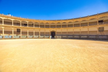 Ronda, İspanya - 4 Eylül 2024: The Plaza de Toros, Ronda 'da bir arenada. Açık mavi gökyüzünün altında boş bir boğa güreşi. Antik mimari ve katmanlı koltuklar dramatik bir sahne yaratır..