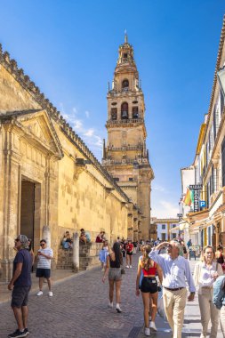 Cordoba, İspanya - 7 Eylül 2024: Cordoba Camii Katedrali, Varsayım Leydimizin Katedrali. Turistler güneşli bir günde tarihi bir kulenin ve antik duvarların önünden geçiyorlar..