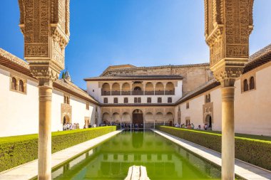 Granada, İspanya - 5 Eylül 2024: Tarihi Alhambra Sarayı 'ndaki Myrtles Sarayı. Yansıtıcı havuzu, karmaşık mimarisi ve gür yeşilliği olan sakin bir avlu..