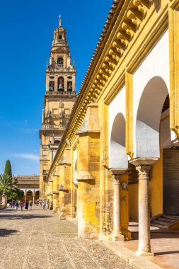 Cordoba, İspanya - 7 Eylül 2024: Cordoba Camii Katedrali, Varsayım Leydimizin Katedrali. Eski mimari: Sarı taş sütunlar ve kemerler mavi gökyüzünün altındaki çan kulesini çerçeveliyor.