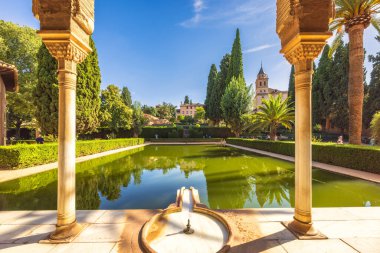 Granada, İspanya - 5 Eylül 2024: Alhambra kompleksi, arka planda yansıyan havuzu ve tarihi mimarisi olan sakin bahçe.