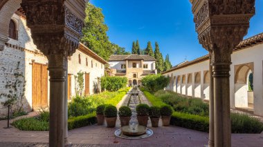 Granada, İspanya - 5 Eylül 2024: The Patio de la Acequia, Alhambra kompleksindeki Generalife sarayının avlusu. Süslü sütunlar, merkezi bir çeşme ile sakin bir bahçe çerçevesi.