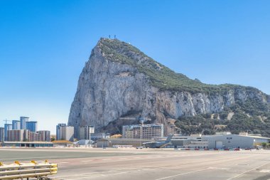 Cebelitarık, Birleşik Krallık - 10 Eylül 2024: Görkemli kaya oluşumu şehir manzarasına hakim, havaalanı pisti açık mavi gökyüzü altında.