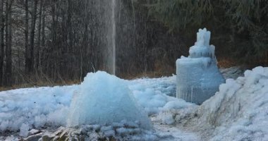 Donmuş çeşme yapılarının serin bir ormanın arka planında yer aldığı bir kış harikalar diyarı sahnesi. Manzara buz ve karla kaplı, soğuk ve sakin bir ortam yaratıyor..