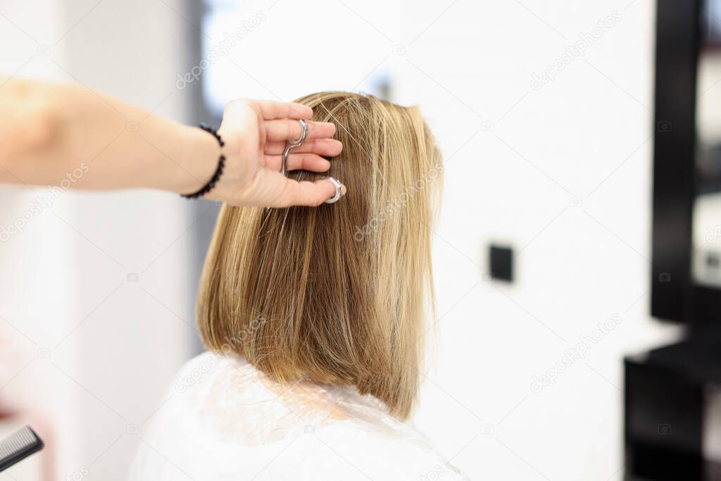 Woman in hairdressing salon cuts her hair
