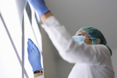 Koruyucu giysili ve maskeli doktor röntgeni inceliyor..