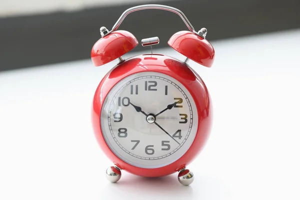Relógio de alarme vermelho fica na mesa branca — Fotografia de Stock