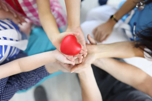 Le mani di adulti e bambini tengono il cuore rosso in mezzo. — Foto Stock