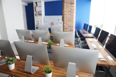 Ofisteki ahşap bir masanın üzerinde birçok gümüş monitör duruyor.