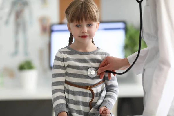 Педиатр прислушивается к сердцу стетоскопом к маленькой девочке в клинике — стоковое фото