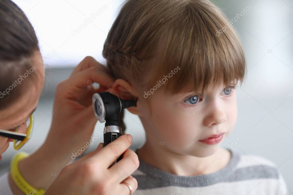 Otorhinolaryngologist examines little girls ear with otoscope in clinic