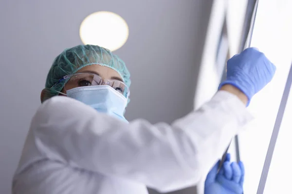 Dokter berkacamata dan masker medis dan sarung tangan memegang gambar X-ray.. — Stok Foto