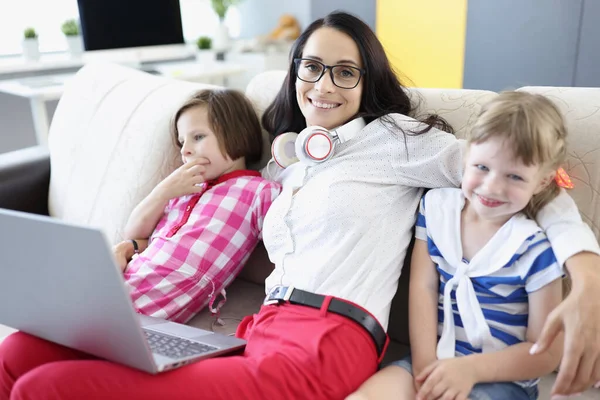 Mujer sonriente está sentado en el sofá con las niñas. — Foto de Stock