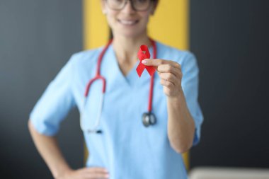 Steteskoplu bir doktor klinikte kırmızı kurdele tutuyor.