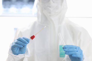 Koruyucu kıyafetli doktor analiz için test tüpü ve raf tutuyor..