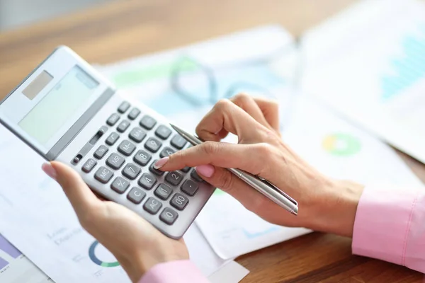 Female hand holds a calculator and pen. — Stock Photo, Image