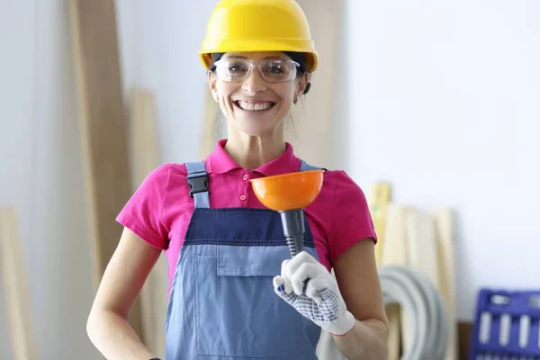 Mosolygó nő sárga kemény kalapban és szemüveg tartja dugattyú a kezében — Stock Fotó