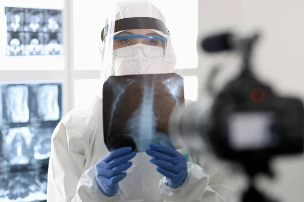 보호용 양복을 입은 의사가 카메라에 X-ray 를 보여 주고 있다. — 스톡 사진