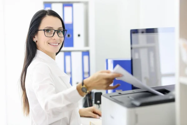 Glimlachend portret van secretaresse die papieren bij de drukker houdt. — Stockfoto