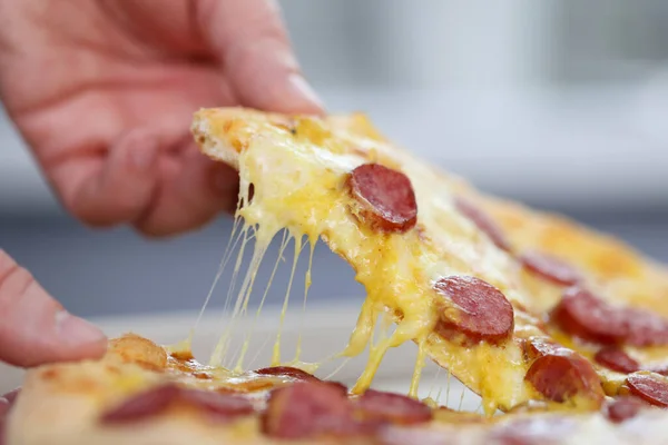 Mans hand holds a slice of pizza. — Stock Photo, Image