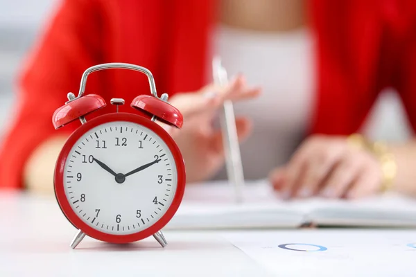 Against the background of businesswoman stands red alarm clock — Stock Photo, Image