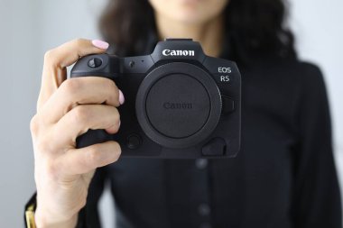 Kadın EOS R5 'i yakın planda tutuyor.