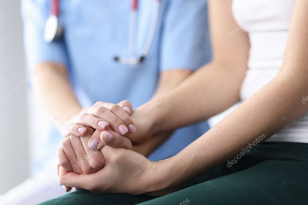 Patients and doctors hands are folded together.