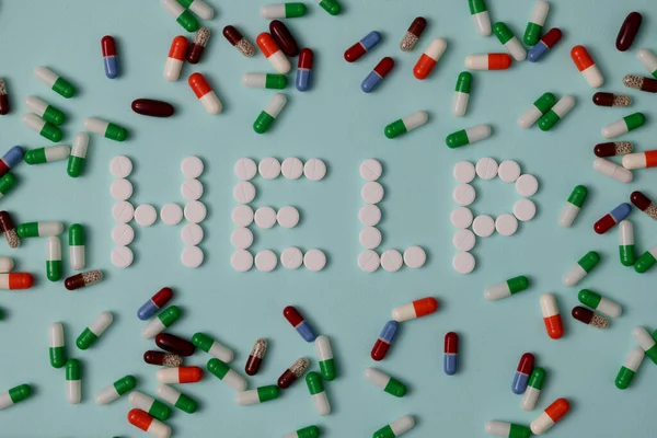 Word Help landing out from white pills as on background of multi-colored capsules — Stock Photo, Image