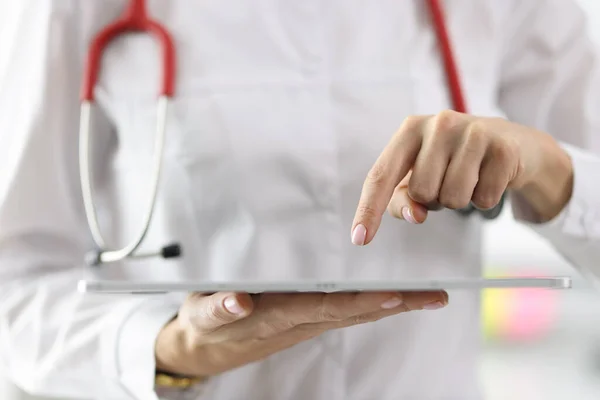 Doctor holding tablet in his hands and pointing at it with his finger closeup
