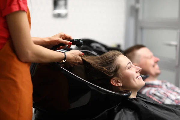 Visitatore felice giacere con la testa in lavabo nero e attendere che il parrucchiere per lavare i capelli con acqua dalla doccia. — Foto Stock