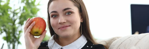 Mädchen sitzt zu Hause mit Apfel in der Hand auf der Couch — Stockfoto