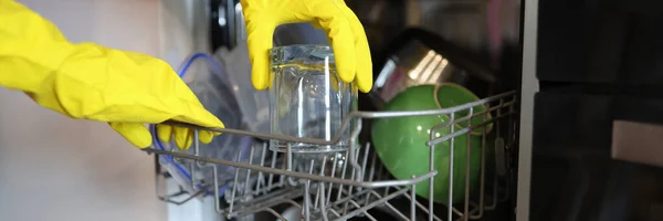 Eine offene Spülmaschine, aus der sauberes Geschirr mit einem Handschuh herausgenommen wird — Stockfoto
