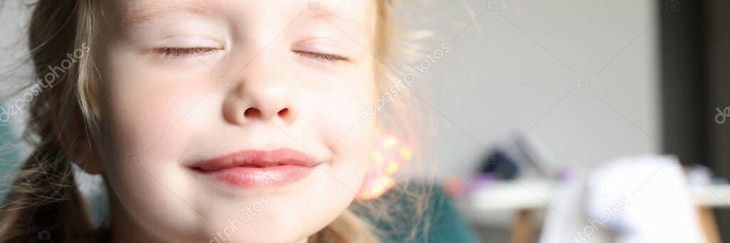 Little girl with closed eyes smiles and holds pens together.