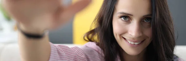 Brünette Frau lächelt und grüßt mit der Hand. — Stockfoto