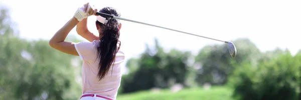 Female golfer stands with her back making swing with club — Stock Photo, Image