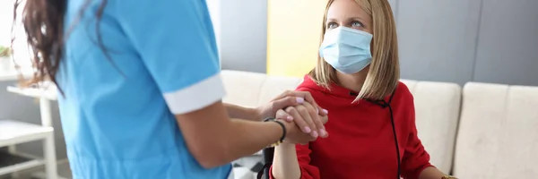 Arzt in Uniform hält Hand einer kranken jungen Frau im Rollstuhl — Stockfoto
