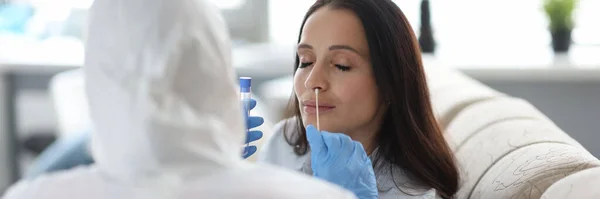 Médecin en combinaison de protection prend du matériel biologique de la femme avec étagère dans la bouche. — Photo