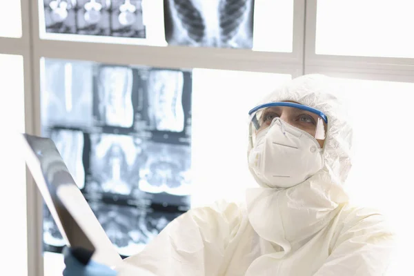 방사선 촬영 장비를 손에 들고 바닥에 뿌려진 항 염병 방지 슈트를 입고 있는 피곤 한 의사 — 스톡 사진