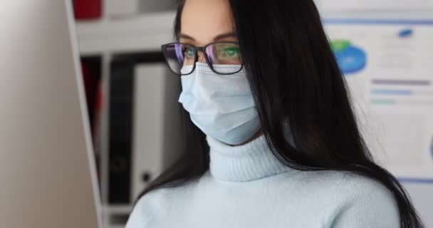 Женщина в защитной медицинской маске и очках работает за компьютером в офисе 4k фильма — стоковое видео