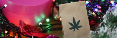 Yeni yıl süsleri, hediyeler, çelenkler arasında masada marihuana dolu kağıt torba yatıyor.