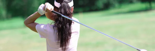 Žena v obleku drží golfovou hůl za zády. — Stock fotografie