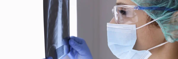 Dokter onbeschermende masker onderzoekt x-ray. — Stockfoto